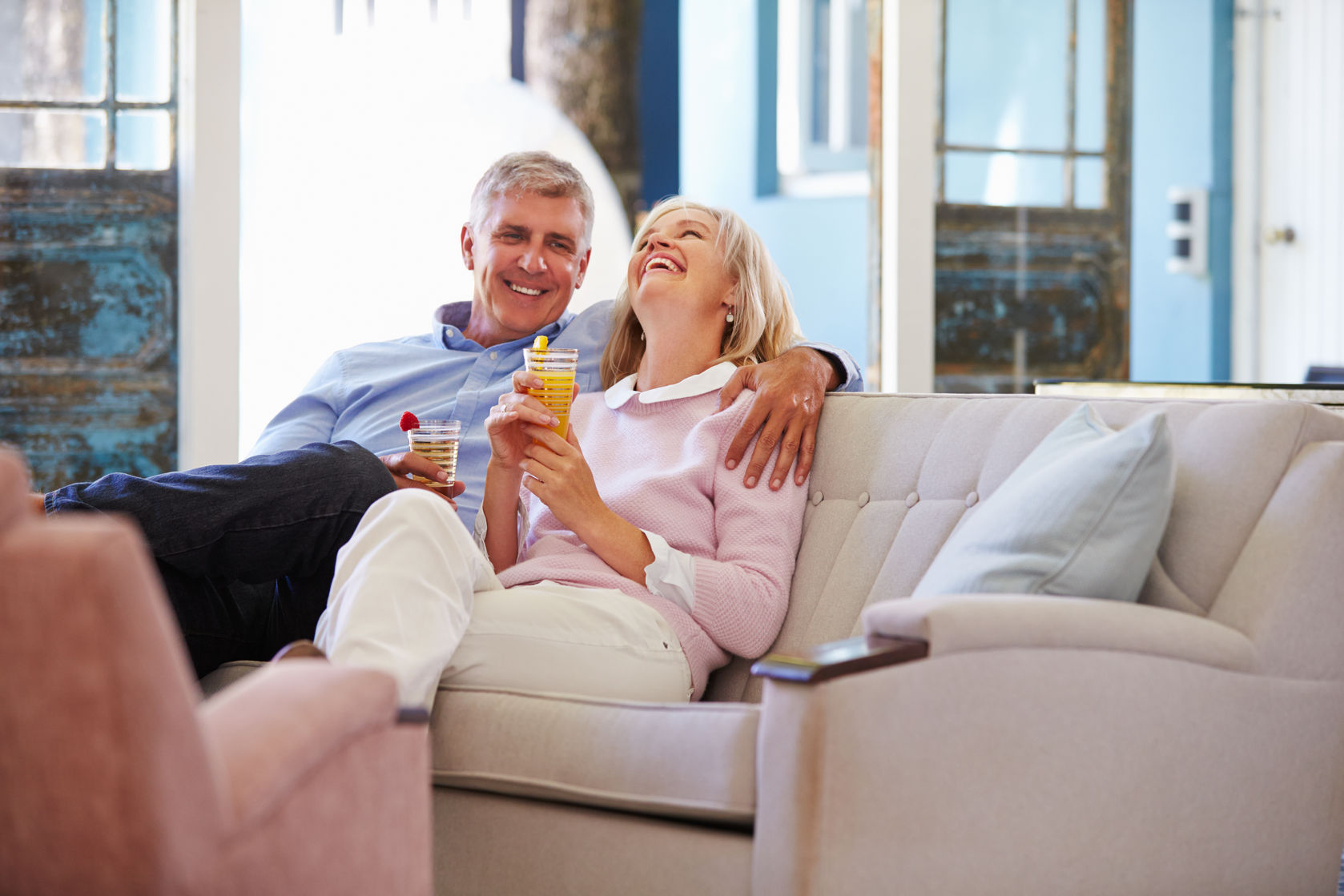 mature couple at home relaxing in lounge with cold drinks